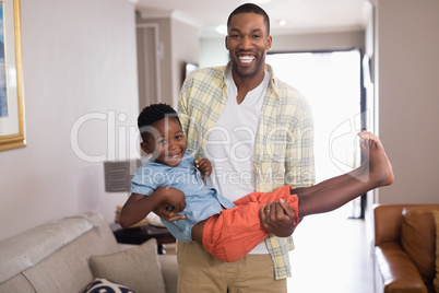 Playful father carrying son in living room