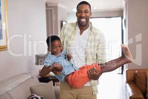 Playful father carrying son in living room