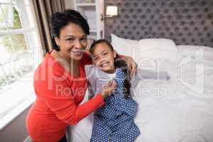 Smiling grandmother helping girl to wear jacket