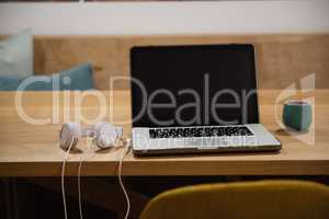 Laptop with headphones and cup on table
