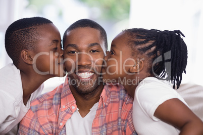 Children kissing smiling father at home