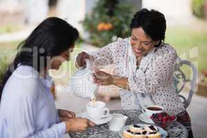 Smiling woman pouring tea in cup for daughter