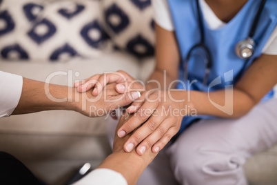 Mid section of doctor touching patient hands