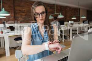 Female executive adjusting smart watch at desk