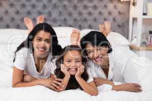 Portrait of cheerful multi-generation family lying on bed