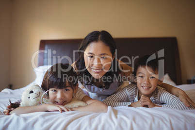 Mother with daughter and son relaxing on bed in bed room