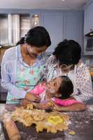 Smiling multi-generation family standing by dough in kitchen