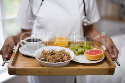 Mid section of nurse holding breakfast tray