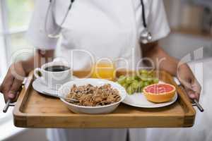 Mid section of nurse holding breakfast tray