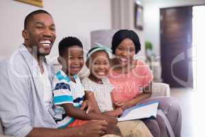 Cheerful family with magazine sitting on sofa at home