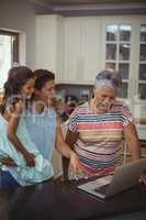 Happy family using laptop in kitchen