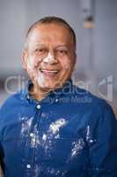Portrait of happy mature man with flour on face and shirt