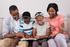 Family reading magazine while sitting on sofa at home