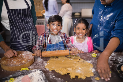 Portrait of smiling siblings preparing food with parents in kitchen