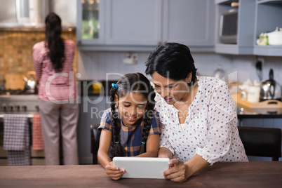 Grandmother and granddaughter using digital tablet in kitchen