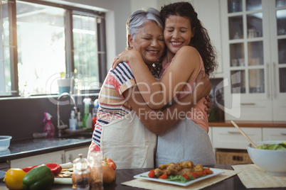 Mother hugging daughter in kitchen