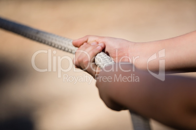 Hands of kid practicing tug of war during obstacle course