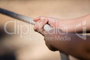 Hands of kid practicing tug of war during obstacle course