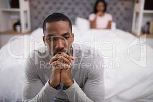 Man sitting while woman lying on bed at home