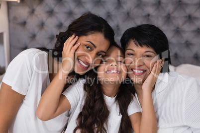 Portrait of smiling multi-generation embracing on bed