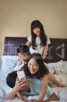 Happy family using mobile phone in the bed room