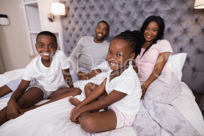 Portrait of smiling family sitting on bed
