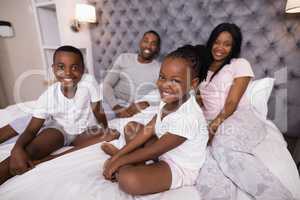Portrait of smiling family sitting on bed