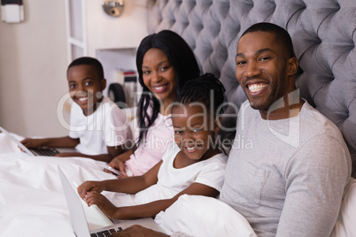 Portrait of smiling family sitting together on bed