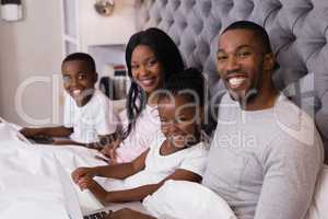 Portrait of smiling family sitting together on bed