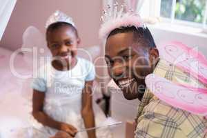Cheerful father and daughter wearing costume wings at home