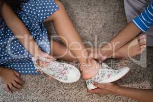 Cropped image of mother helping daughter to wear shoe
