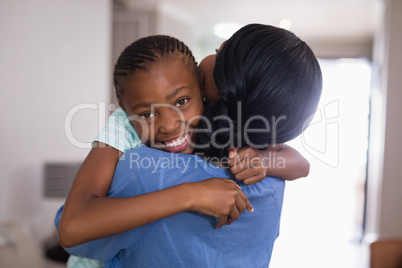 Happy girl embracing mother in living room at home