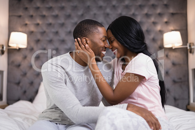 Happy young couple embracing in bedroom