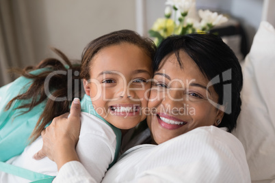 Close up of happy mature woman embracing girl on bed