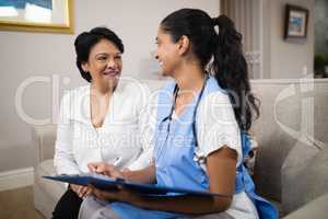 Smiling doctor with patient sitting on sofa