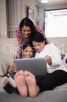 Smiling multi-generation family using laptop together