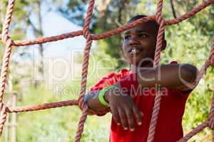 Happy boy leaning on net during obstacle course