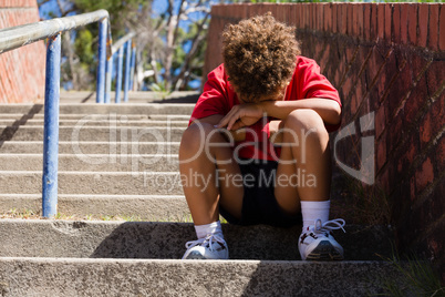 Upset boy sitting on staircase in the boot camp