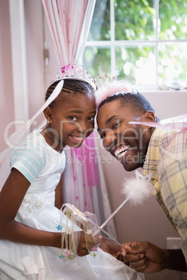 Cheerful father and daughter holding wands while wearing costumes