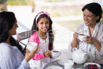 Portrait of smiling girl having breakfast with mother and grandmother