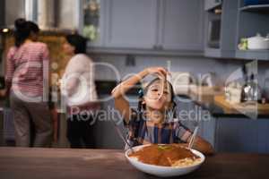 Girl eating spaghetti in kitchen