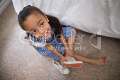 Smiling girl wearing shoe at home