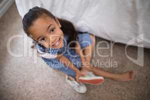 Smiling girl wearing shoe at home