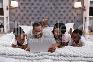 Smiling family using laptop while lying together on bed