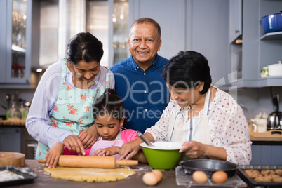 Portrait of smiling man with family preparing food in kitchen