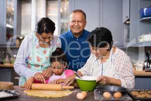 Portrait of smiling man with family preparing food in kitchen