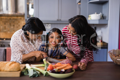 Portrait of girl preparing food with mother and grandmother in kitchen
