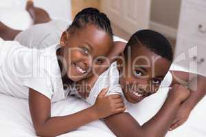 Portrait of smiling siblings lying on bed