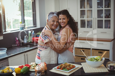 Mother hugging daughter in kitchen