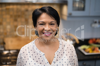 Portrait of smiling mature woman standing in kitchen